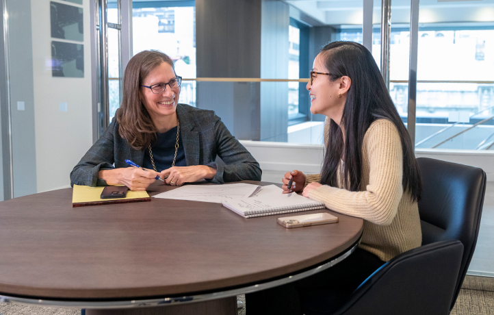 Two Viking team members sitting at a round table, smiling and discussing notes.