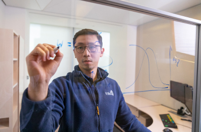 Viking team member writing equations on a glass board in an office setting.