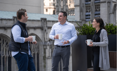 Three Viking team members enjoying a coffee chat on an outdoor terrace.