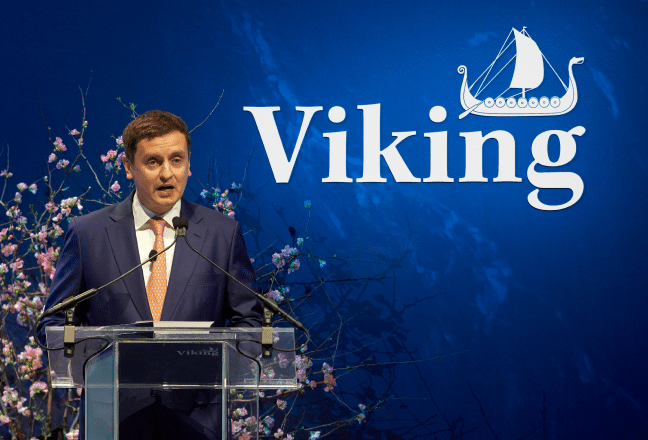 Viking team member standing at a podium with the Viking logo in the background.