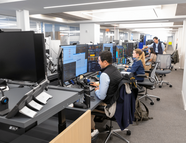 Viking team members working at desks on the trading floor, surrounded by multiple screens.