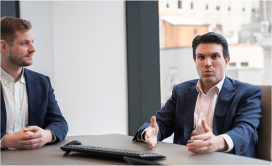Two Viking team members engaged in a discussion at a table in an office setting.