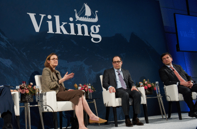 Three Viking team members sitting on a stage with the Viking logo in the background. One team member is gesturing as they speak.